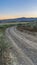 Vertical frame Curving dirt road with view of the valley and mountain against blue sky