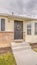 Vertical frame Facade of home with yard pathway and stairs in front of the door with wreath