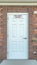 Vertical frame Fire Riser Room sign on the white wood door of a building with red brick wall