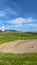 Vertical frame Golf course with sand bunker and vibrant fairway under blue sky on a sunny day