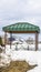 Vertical frame Green cabana with barbecue grill and picnic table at a snow covered park