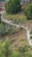 Vertical frame Narrow hiking trail curving through the grassy terrain of a mountain