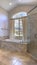Vertical frame Oval bathtub in front of the arched window of a bathroom with tiled floor