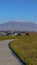 Vertical frame Paved road on a lush grassy hill overlooking beautiful houses on a sunny day