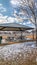 Vertical frame Pavilion with tables benches and melted snow against homes and cloudy blue sky