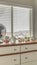 Vertical frame Potted cacti and electric fan on wooden cabinet against bay window of a home