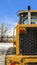 Vertical frame Rear view of a loader against snow covered ground and cloudy blue sky in winter