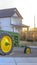 Vertical frame Replica of a tractor at a park with houses and sky in the background