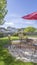 Vertical frame Seating area on a stone patio under the shade of a red umbrella on a sunny day