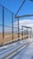 Vertical frame Sunlit bleachers overlooking a vast sports field on the other side of the fence