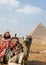 Vertical front view of camel with colorful apparel sitting in front of the great pyramid of Giza in Cairo, Egypt. Animal