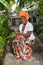 The vertical full body of a joyful African American woman wearing a bright colorful national dress sits in the garden