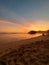 Vertical full length view through the sandy beach with golden sea water at sunset