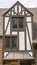 Vertical Gabled dormer with decorative windows against brick wall and roof of building