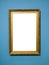 Vertical golden wooden picture frame on blue wall