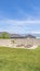 Vertical Grassy yard with view of rooftops lake and snow capped mountain under blue sky