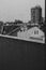 Vertical grayscale shot of buildings from a wet window after rain