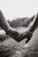 Vertical grayscale shot of a loving couple& x27;s hands, outdoors