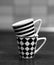 Vertical grayscale shot of mugs with striped and chess tile patterns