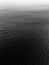 Vertical grey scale shot of the waves on the ocean captured from a high angle