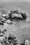 Vertical greyscale of the rocks in the middle of the ocean captured on a cloudy day