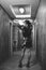 Vertical greyscale shot of an attractive female posing in a nice dress in a beautiful hallway
