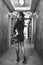 Vertical greyscale shot of an attractive female posing in a nice dress in a beautiful hallway