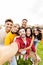 Vertical group portrait of multiracial young friends taking selfie with phone