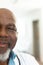 Vertical half face portrait of smiling senior african american male doctor, with copy space