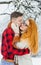 Vertical half-length portrait of the charming loving couple spending time in the winter forest. The handsome groom is