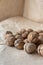 Vertical handful of walnuts in the shell on an old mint kraft paper, a brown background, a warm beige pattern