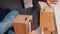 Vertical, happy young man with cardboard box on the head performing hand dance in the new apartment