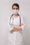 Vertical head shot concept. Young beautiful woman doctor in medical mask in a white coat on an isolated white background