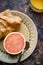 Vertical high angle closeup shot of a croissant and half of a grapefruit on the breakfast table