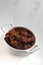 Vertical high angle shot of a bowl of meat mixed with vegetables on a white background