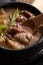 Vertical high angle shot of a bowl of meat soup with a wooden spoon on a table