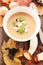 Vertical high angle shot of a bowl of mushroom soup with vegetables on a wooden surface