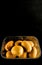 Vertical high angle shot of kiwis in a plastic bowl with a black background