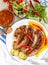 Vertical high angle shot of a plate of cooked sausage and vegetables and salad on a table