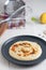 Vertical high angle shot of a plate of hummus on the kitchen counter near some equipment