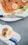 Vertical high angle shot of a plate of uncooked fish with lemons and herbs on an outdoor table