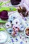 Vertical high angle shot of some blue and purple vegan donuts surrounded by flowers on a table