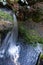 Vertical high angle shot of the water flowing on the mossy rocks