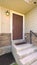 Vertical Home facade with concrete stairs leading to the brown wooden front door