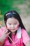 Vertical image. Asian girl sits to rest from Easter activities. Children paint watercolor cartoons on cheeks.