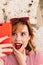 Vertical image of a beautiful woman smiling and taking a selfie in the street with her smartphone for her social networks.