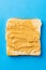 Vertical image of bread slice with peanut butter on blue background