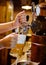 Vertical image close up view female barman hands pouring beer in mug