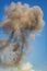 Vertical image of Column of smoke with tornado against blue sky from munitions explosion