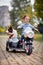 Vertical image of cute little girl  driving electrical motorcycle toy with sidecar and her dog in it, smiling